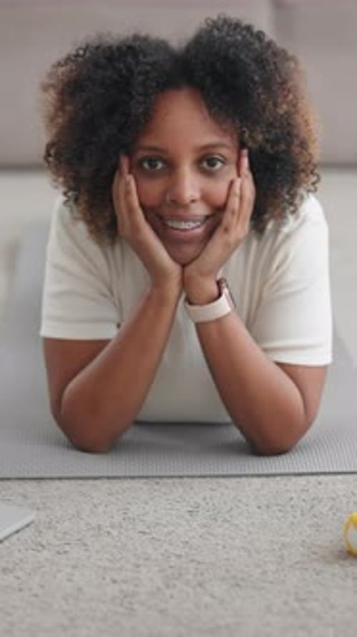 Smiling Woman Lying on a Yoga Mat Indoors