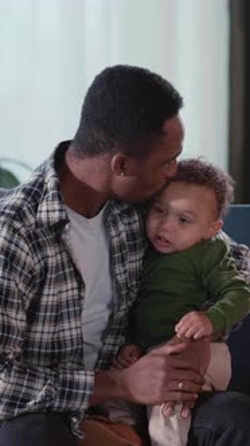 Dad Holding Infant in Lap Smiling Brightly