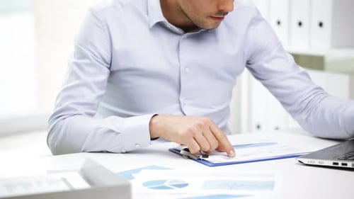 Busy businessman works with laptop and paperwork in a modern office