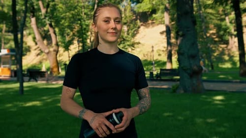Young Woman in Park Holding Water Bottle