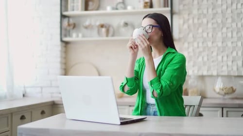 Young Woman Works on Laptop in Kitchen