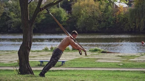 Jeune homme actif fait de l'exercice à l'extérieur avec des sangles.