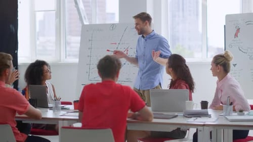 Young businessman talking with multiethnic colleagues in modern office boardroom
