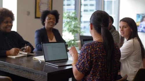 Businesswomen collaborating and planning strategy at laptops in office meeting