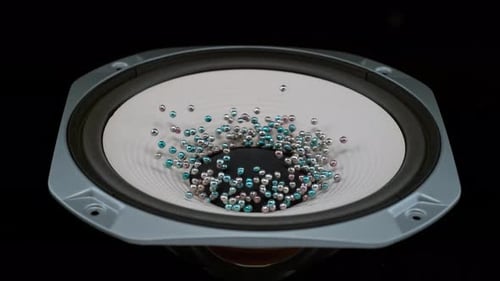 Speaker cone vibrating causing beads to bounce abstract