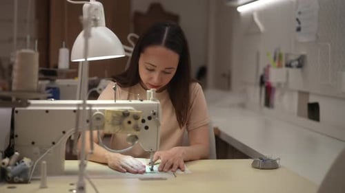 Woman Sews Fabric With a Sewing Machine