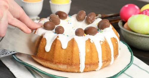 Woman cutting Easter cake at wooden table, closeup