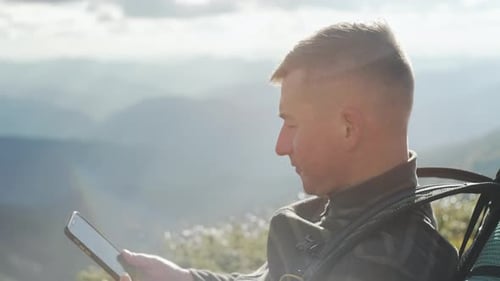 A Man with a Backpack Takes a Picture of the Landscape on His Phone While Hiking