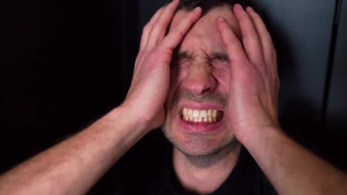 Nahaufnahme eines jungen Mannes, der vor Kopfschmerzen und Schmerzen schreit und schreit