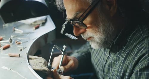 Slow motion of experienced goldsmith working on a handmade jewelry bracelet chain of precious meta
