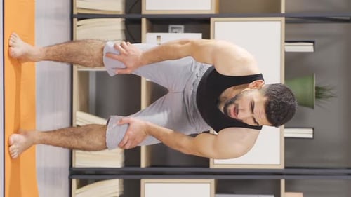 Man Stretches Torso Downward on Yoga Mat Indoors