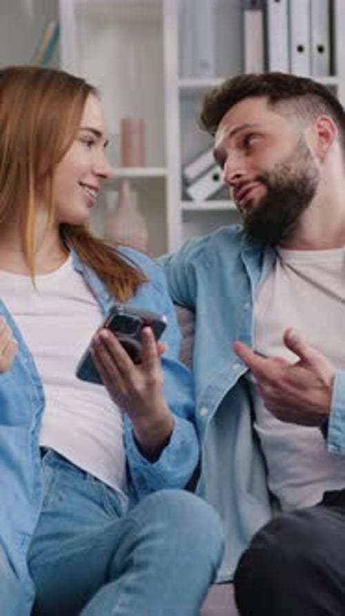 Smiling Couple Looking at Phone Together Indoors