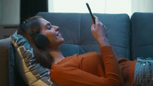 Junge Frau liegt zu Hause mit ihrem Smartphone-Gerät auf der Couch Frau ruht sich aus