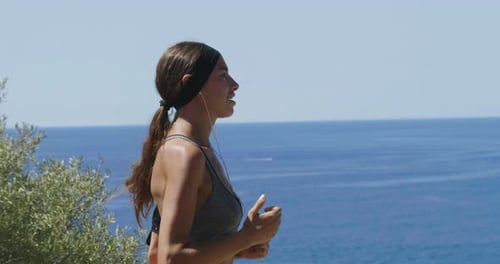 a girl with athletic body and sculpted abdominal is jogging by the sea on a sunny day. concept of