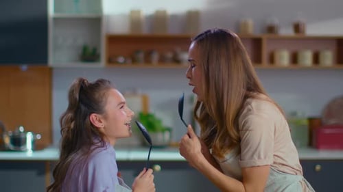 Mother and Daughter Singing with Cooking Utensils