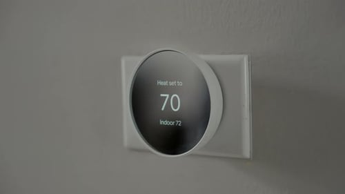 Adjusting a Smart Thermostat on Wall Indoors
