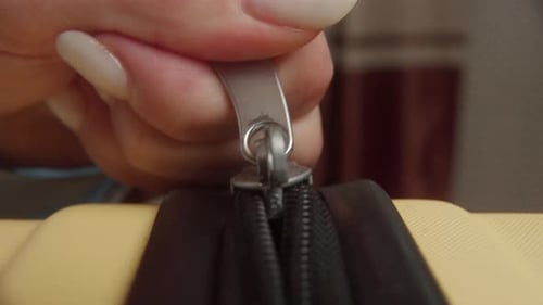 Woman Skillfully Closing the Zipper on a Vibrant Yellow Suitcase
