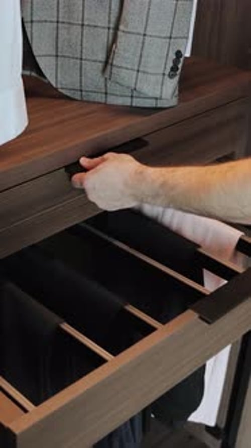 Gros plan d'une main ouvrant un tiroir en bois dans une armoire avec des objets, intérieur moderne/vidéo verticale