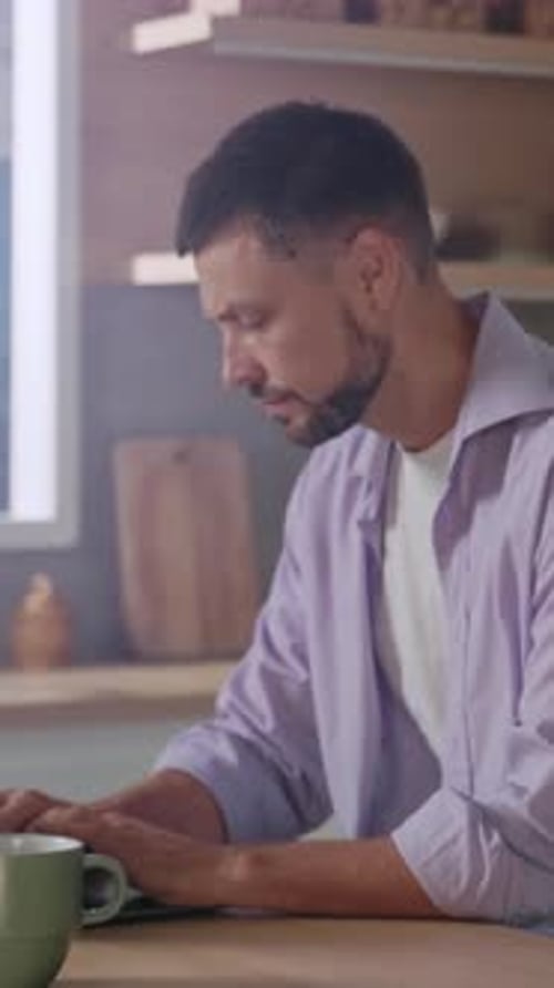 Man Working at Laptop Talks on Mobile Phone