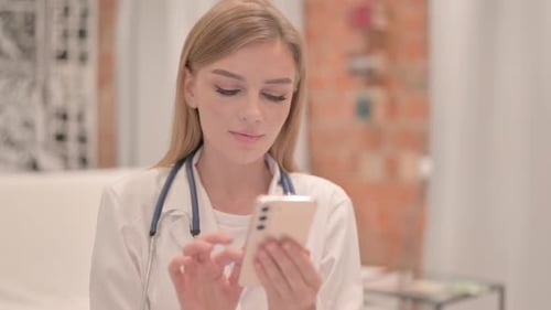 Young Woman Doctor Using Smartphone in Clinic