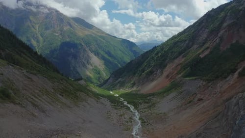 Aerial View of a Mountain River Flowing Between Cloudcovered Mountain Peaks
