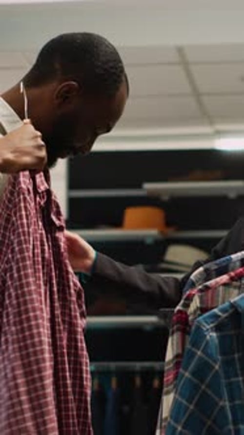 Vertical Video Store Assistant Giving Clothes to Man to Try on