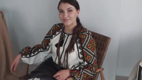 Stylish Woman in Embroidered Top Posing in Chair