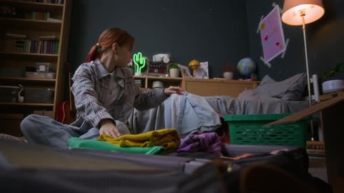 Female Zoomer Placing Clothes in Suitcase Packing Stuff for Moving