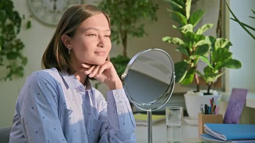 Young Attractive Woman with Natural Makeup Looking in Mirror