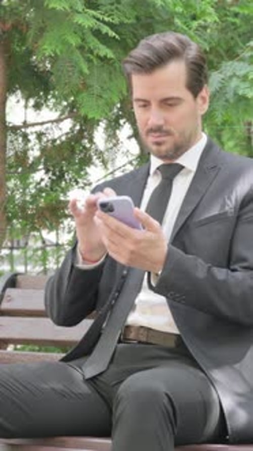 Professional Man Using Mobile Phone on Park Bench