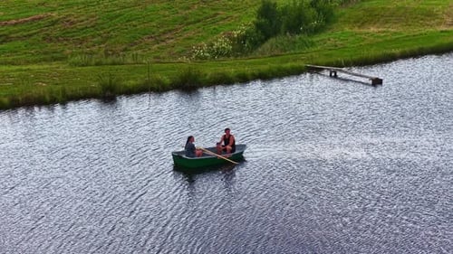 Slow Motion Aerial Orbit of Couple Rowing Boat on Peaceful Pond