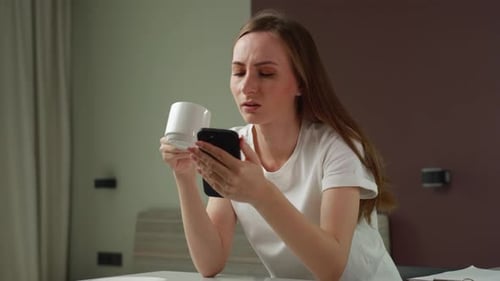 Woman Using Phone and Drinking Coffee at Home