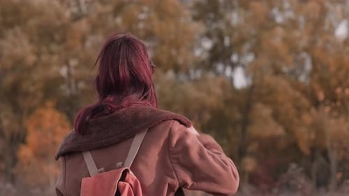 Woman with Backpack Smiling and Putting on Sunglasses