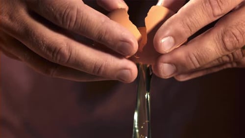 Hände eines Mannes mit einem fallenden rohen Ei, gefilmt auf einer Hochgeschwindigkeitskamera mit 1000 Bildern pro Sekunde