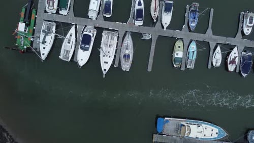 Top down aerial drone view above luxury moored private marina sailing ships and yacht boats followin