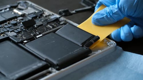Techniker in Handschuhen zerlegen den Laptop vorsichtig zur Reparatur