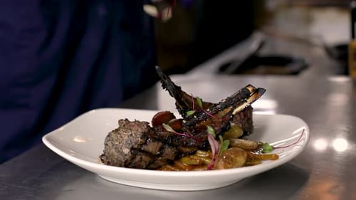 Chef Plating Delicious Rack of Lamb in Kitchen