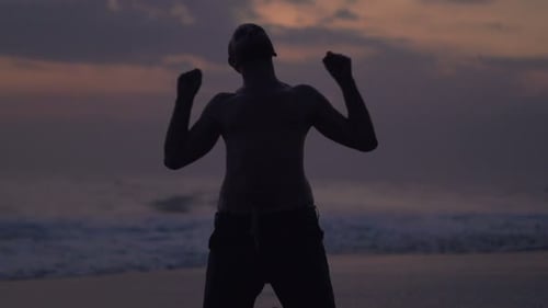 Triumphant Man on Beach at Dusk
