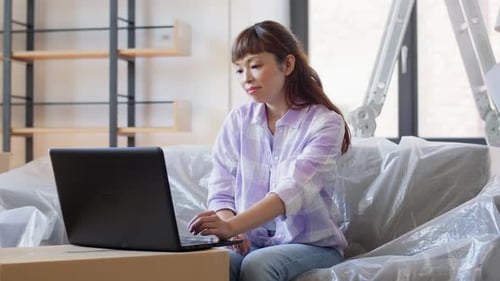Moving, People and Real Estate Concept - Asian Woman with Laptop Computer