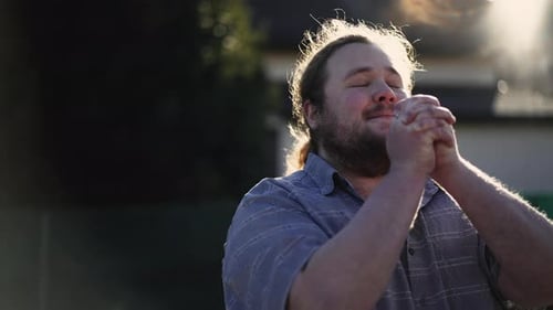 Man Prays with Clasped Hands in Sunlight
