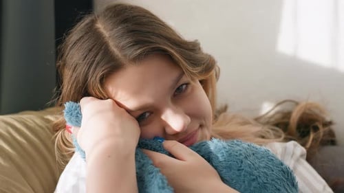 Girl Hugs Blue Plush Toy on Couch Indoors