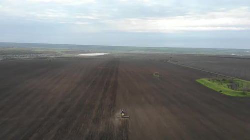 Blue tractor planting sunflower with yellow planter on the field in Ukraine