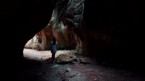 Exploração de cavernas, explorando uma caverna. Jovem exploradora caminha por um caminho estreito em cavernas