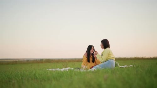 Two Girls Enjoying Picnic Outdoors at Sunset
