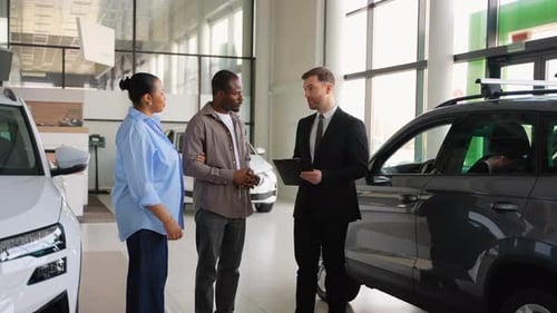 Happy Couple Receiving Car Keys From Salesman in Dealership