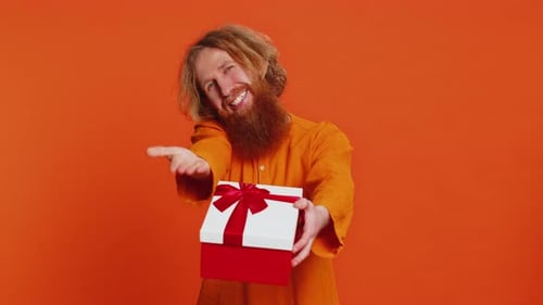 Smiling Man Giving a Wrapped Gift on Orange Background