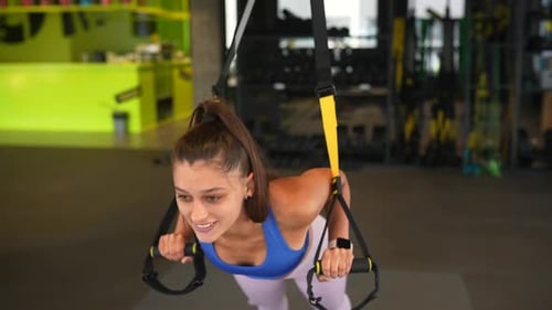 Young Athletic Woman Doing Exercises with Trx Fitness Straps in the Gym