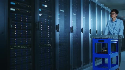 Dans un centre de données moderne : un ingénieur informatique travaille avec des baies de serveurs, utilise un ordinateur portable pour la maintenance et
