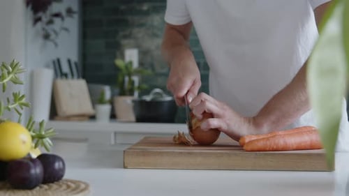 Man Prepares Onion in Bright Kitchen