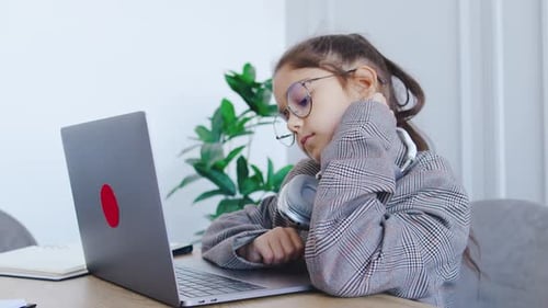 In a Cozy Study a Young Girl Wearing Headphones is Focused on Her Laptop Deeply Absorbed in Her